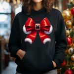 Black hoodie with red santa bow design featuring white fur trim and buckle, next to decorated Christmas tree