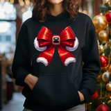 Black hoodie with red santa bow design featuring white fur trim and buckle, next to decorated Christmas tree
