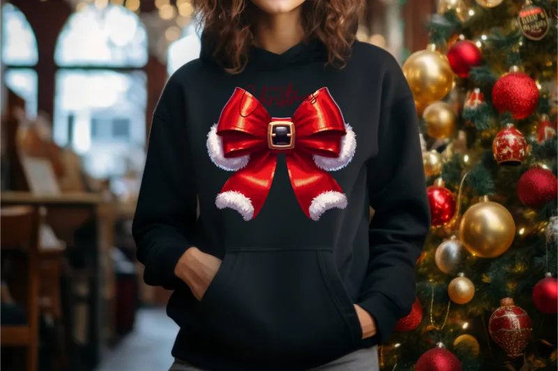 Black hoodie with red santa bow design featuring white fur trim and buckle, next to decorated Christmas tree