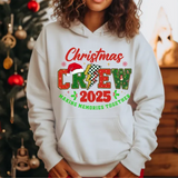 White hoodie with Christmas Crew 2025 design, decorated Christmas tree in background