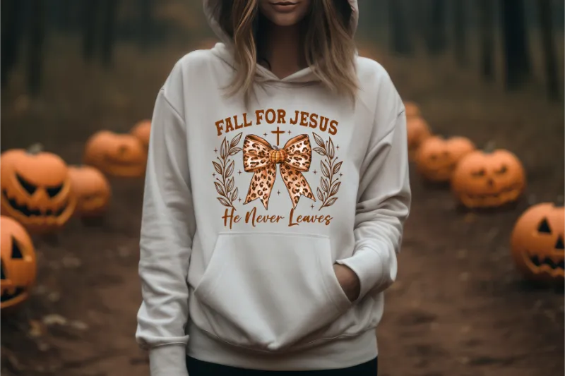 White hoodie with Fall for Jesus He Never Leaves text and leopard print bow design, surrounded by carved pumpkins