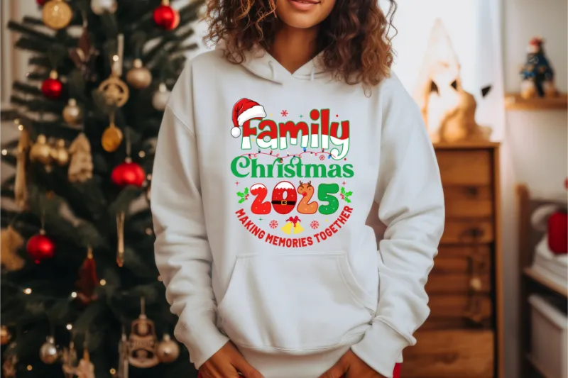White hoodie with Family Christmas 2025 design, making memories together text, Santa hat graphic, Christmas tree background