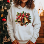 White hoodie with christmas bells, pinecones, and red berries print, christmas tree in background