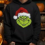 Green grinch character with santa hat printed on black hoodie surrounded by halloween pumpkins