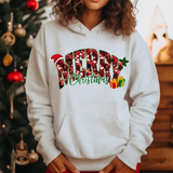 White hoodie with colorful Merry Christmas text and holiday decorations, Christmas tree in background
