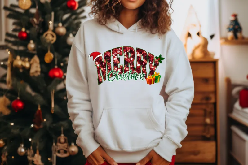 White hoodie with colorful Merry Christmas text and holiday decorations, Christmas tree in background