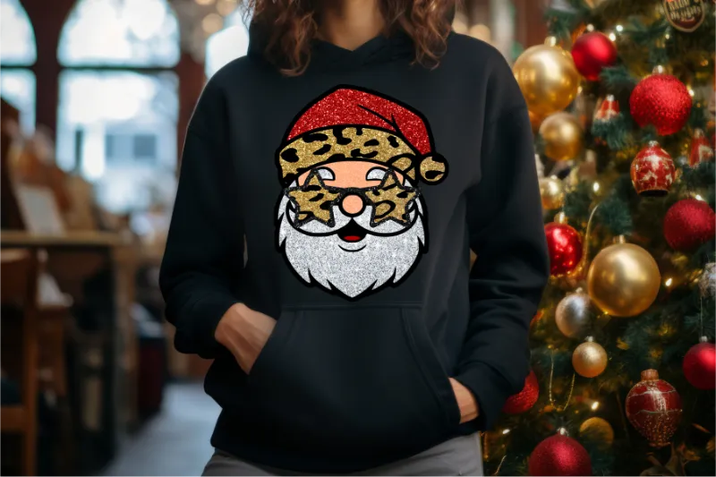 Black hoodie with glittery red leopard print Santa Claus design, Christmas tree ornaments in background