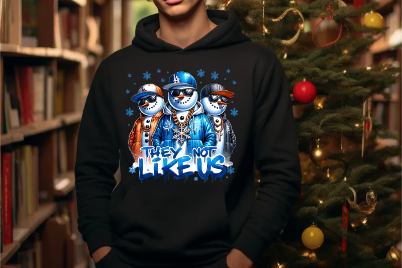 Black hoodie with three stylized snowmen wearing baseball caps and sunglasses, text reads they not like us