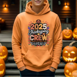 Orange hoodie with 2025 Thanksgiving Crew design, surrounded by carved jack-o-lantern pumpkins