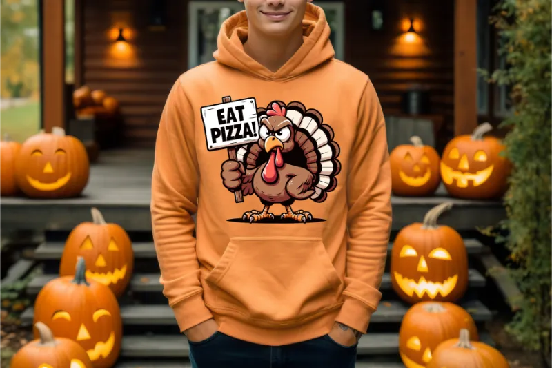Orange hoodie with cartoon turkey holding Eat Pizza sign, surrounded by carved Halloween pumpkins