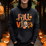 Black hoodie with fall vibes printed design, surrounded by lit jack-o-lantern pumpkins