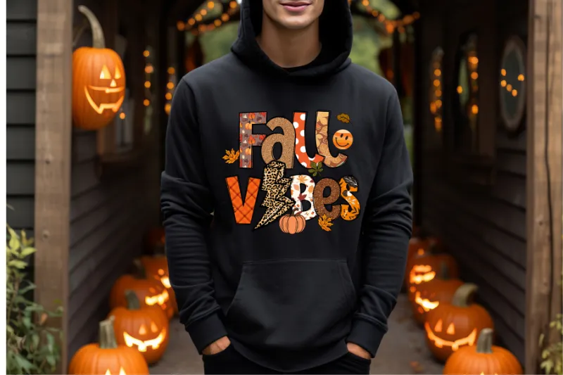 Black hoodie with fall vibes printed design, surrounded by lit jack-o-lantern pumpkins
