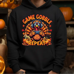 Black hoodie with cartoon turkey wearing headphones holding game controller surrounded by pumpkins