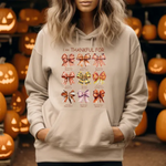 Beige hoodie with colorful bow illustrations and text I am Thankful For displayed against jack-o-lantern pumpkin background
