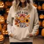 Beige hoodie with Just a Girl Who Loves Fall design featuring pumpkin, sunflower, autumn leaves, and football