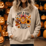 Beige hoodie with Just a Girl Who Loves Fall design featuring pumpkin, sunflower, autumn leaves, and football
