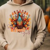 Cream hoodie with colorful turkey design featuring Stay Blessed Yall text and autumn leaves, with pumpkins in background