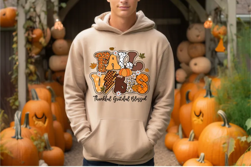 Cream hoodie with colorful fall-themed Fall Vibes design surrounded by orange pumpkins